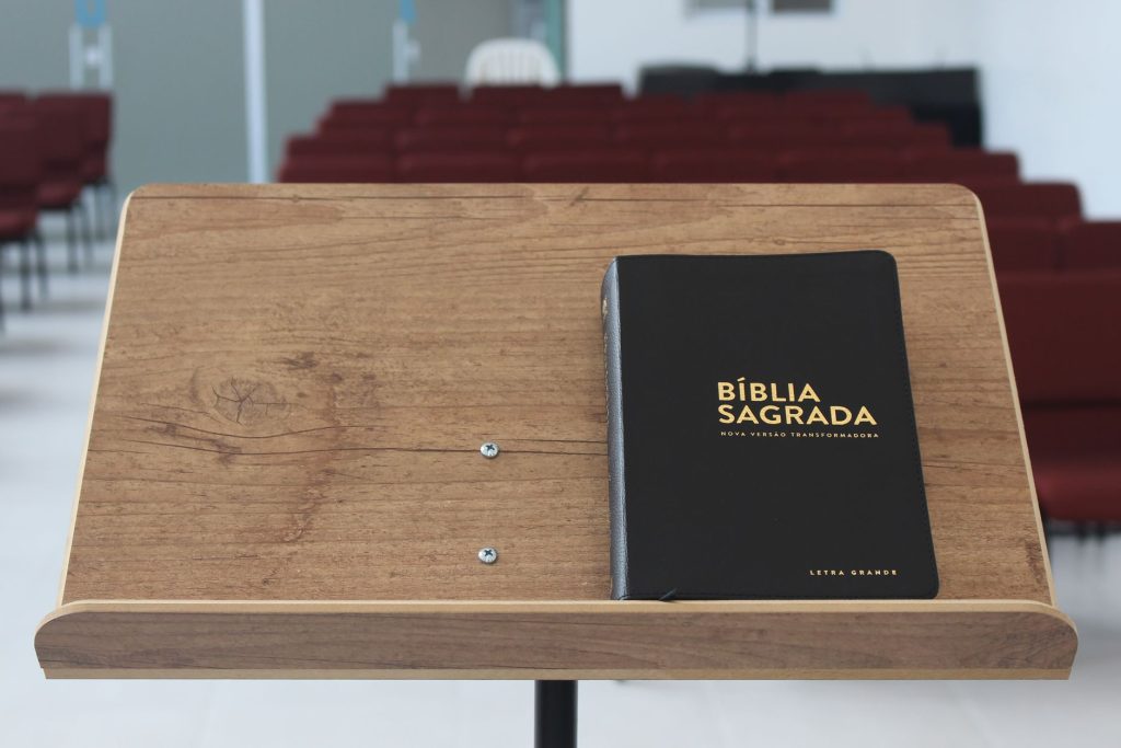 Close-up of a Bible on a wooden lectern in an empty church auditorium.