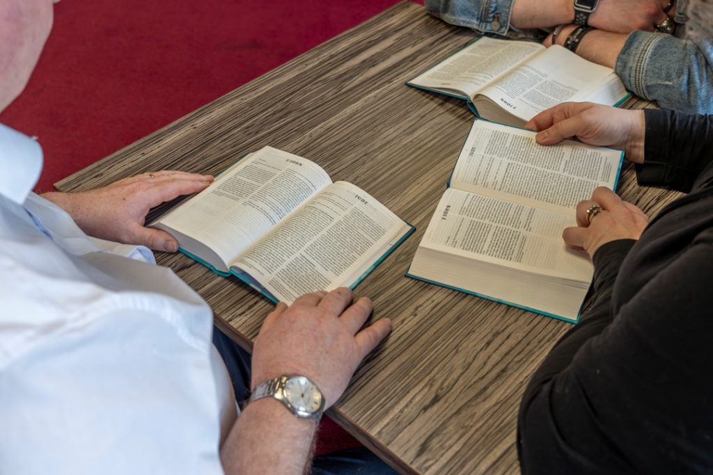 Um Grupo De Pessoas Sentadas Em Uma Mesa Com Livros Abertos HQorO9JqAEE