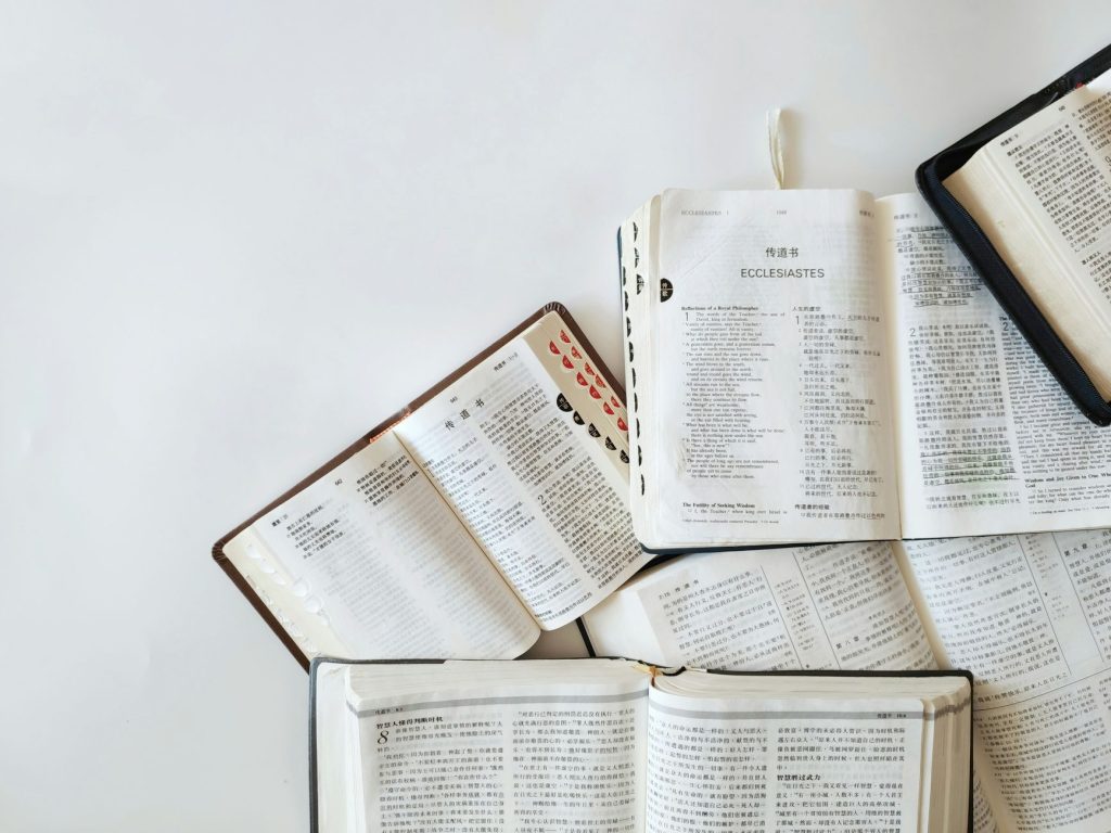 Multiple Bibles open on a white background showing text from Ecclesiastes in different languages.