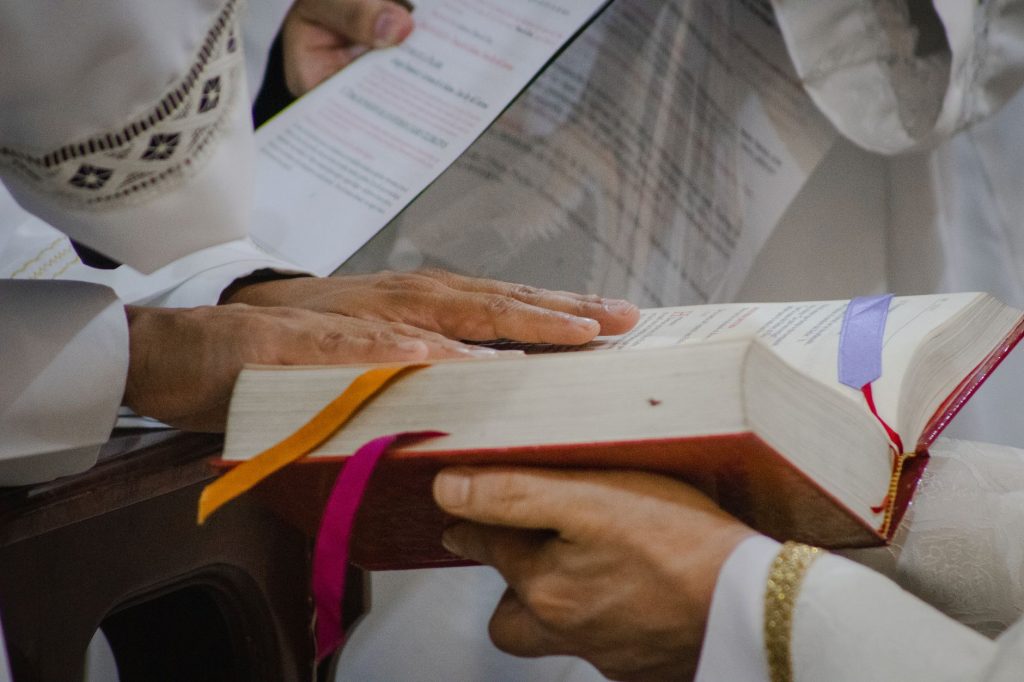 Priest during a sacred ceremony holding a holy book with ribbons. A spiritual moment captured indoors.