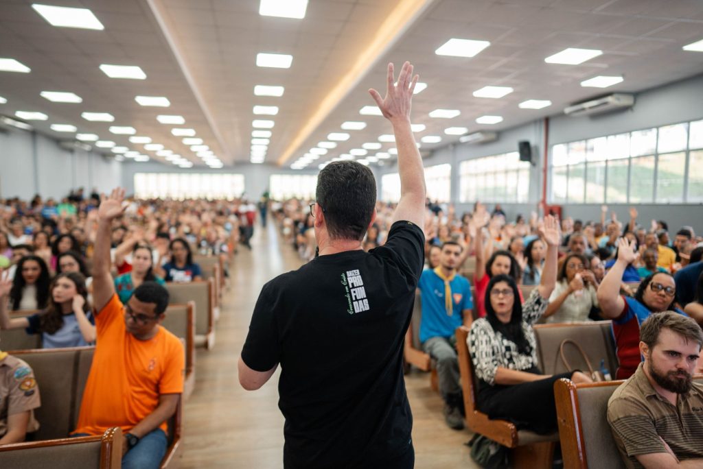 Speaker leads interactive session in packed auditorium with diverse audience.