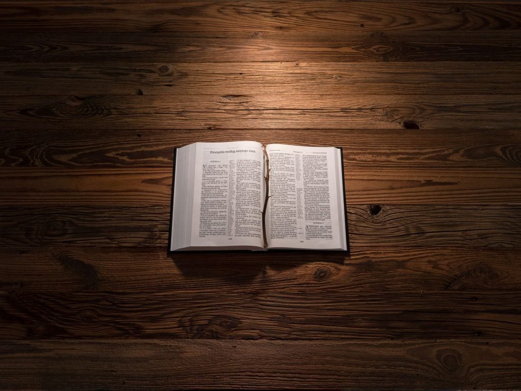 An open Bible on a wooden table, softly lit, symbolizing reflection and spirituality.