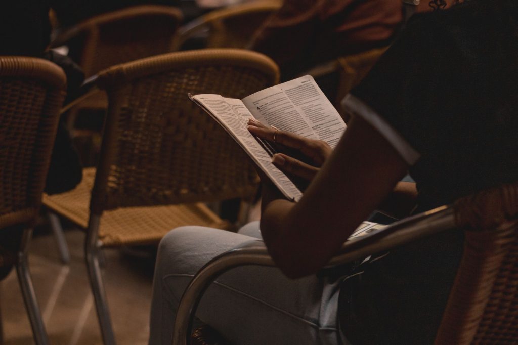 Person reading a book in a dimly lit room, creating a warm and intimate atmosphere.