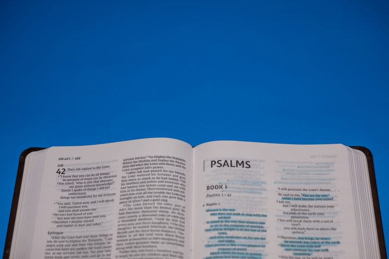 Open Bible displaying Psalms against a vibrant blue backdrop.